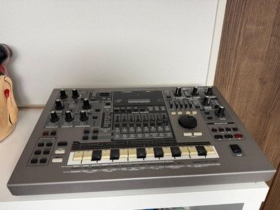 Grauer Hardware-Sequencer mit Reglern, Tasten und zentralem Display