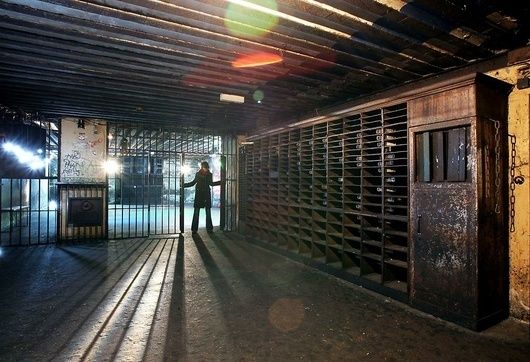 Dunkler Tresorraum mit Gittertoren, Schließfächern und einer Person im Gegenlicht